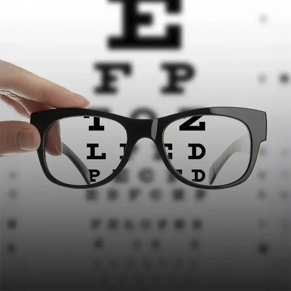 Pair of eyeglasses held in front of a Snellen eye chart, illustrating clear vision correction.